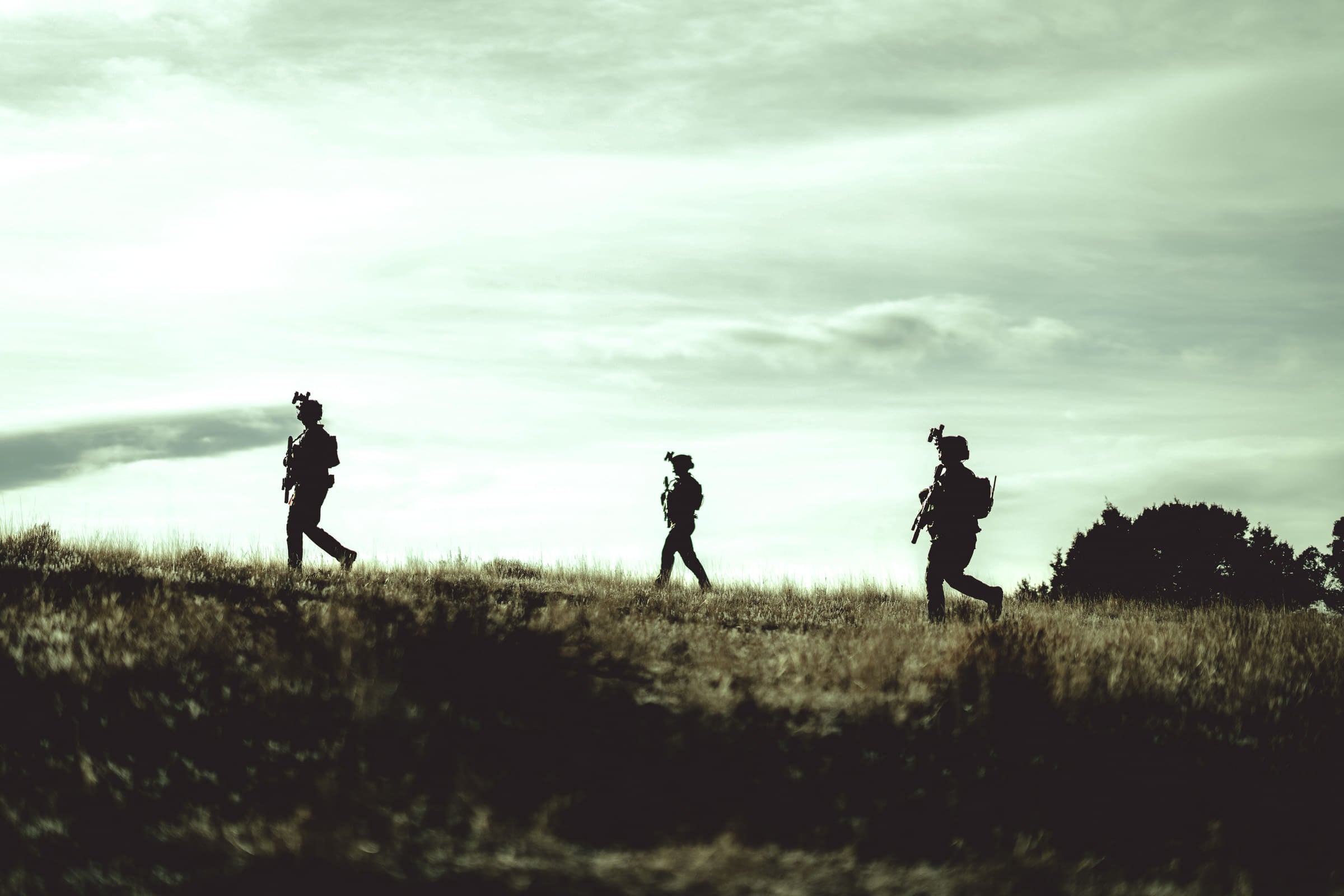 Three operators moving in file along a ridge line against an open sky