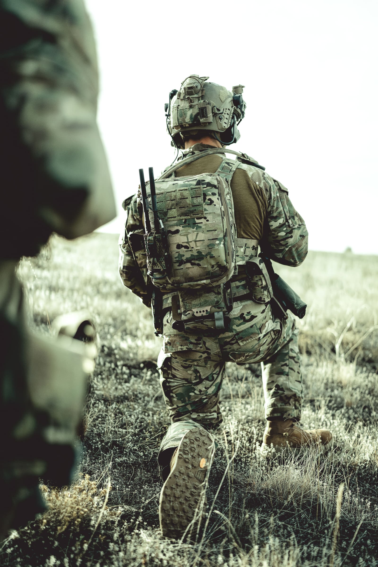 Operator advancing away through open grassland in full kit