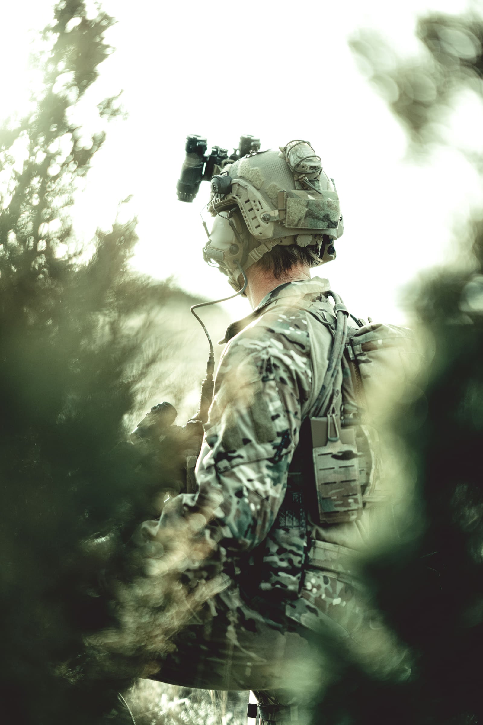 Operator moving behind brush, framed through the foliage